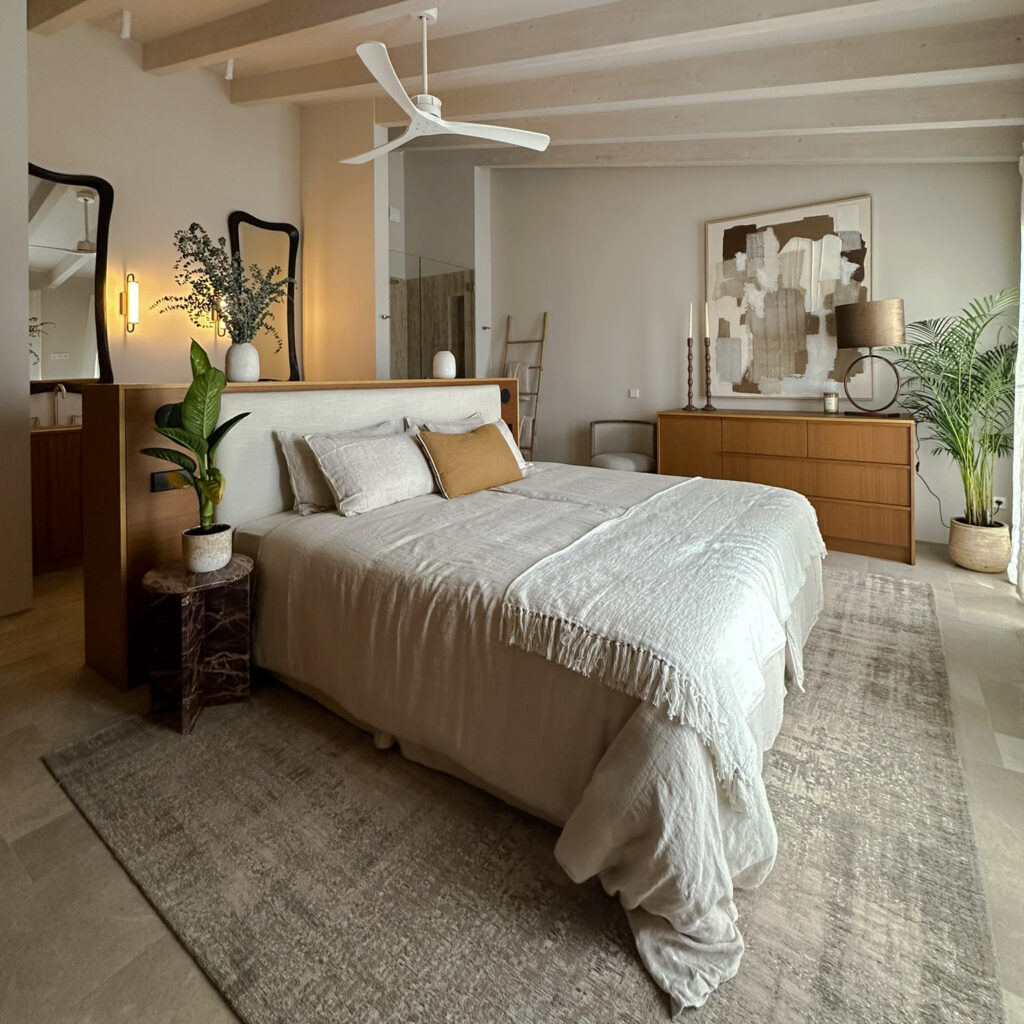 Bespoke chest of drawers in iroko wood, with Light & Living lamp, Vical wall art. Create ceiling fan. Light & Living mirrors with black wooden frame, Grohe sanitary fittings and Aromas del Campo wall lights. Vical marble bedside tables. Maison du Monde cushions & accessories. Natural stone floor in Gris Lara. Louis de Poortere rug. Farrow & Ball Schoolhouse White paint on the walls.