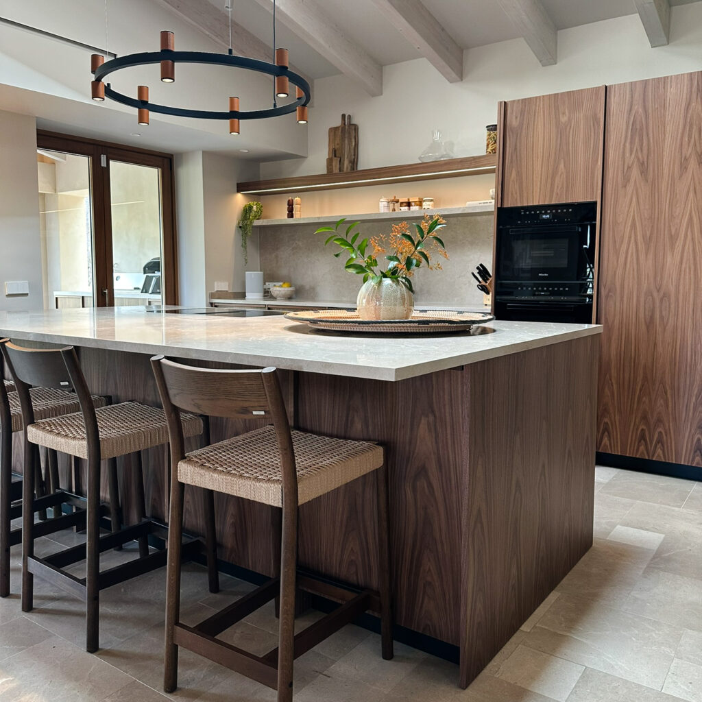 Bespoke walnut veneer kitchen with integrated Miele appliances and Kave Home bar stools. Aromas del Campo Valencia pendant light.