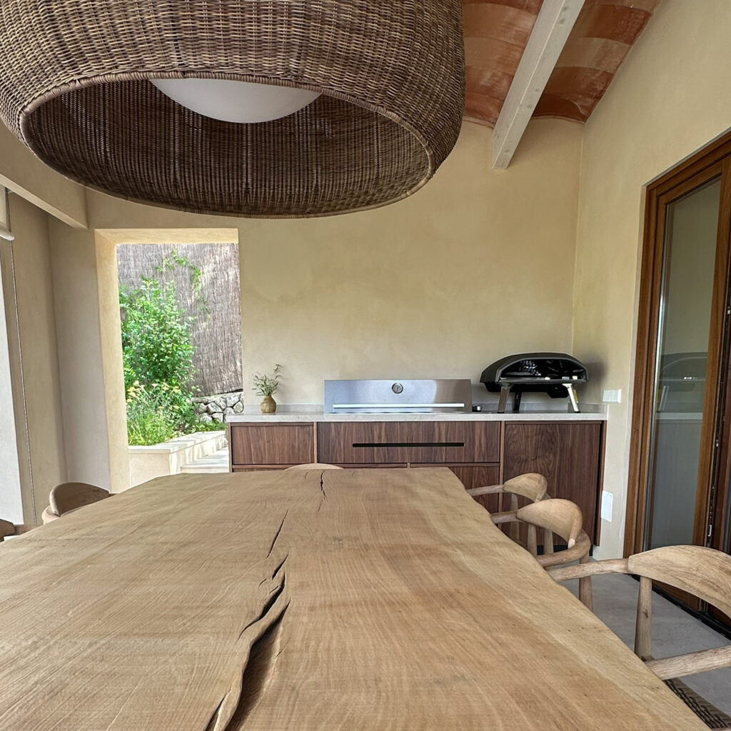 Bespoke barbecue unit with Beefeater gas BBQ & Ooni gas pizza oven. Large outdoor table & Bover pendant light above.