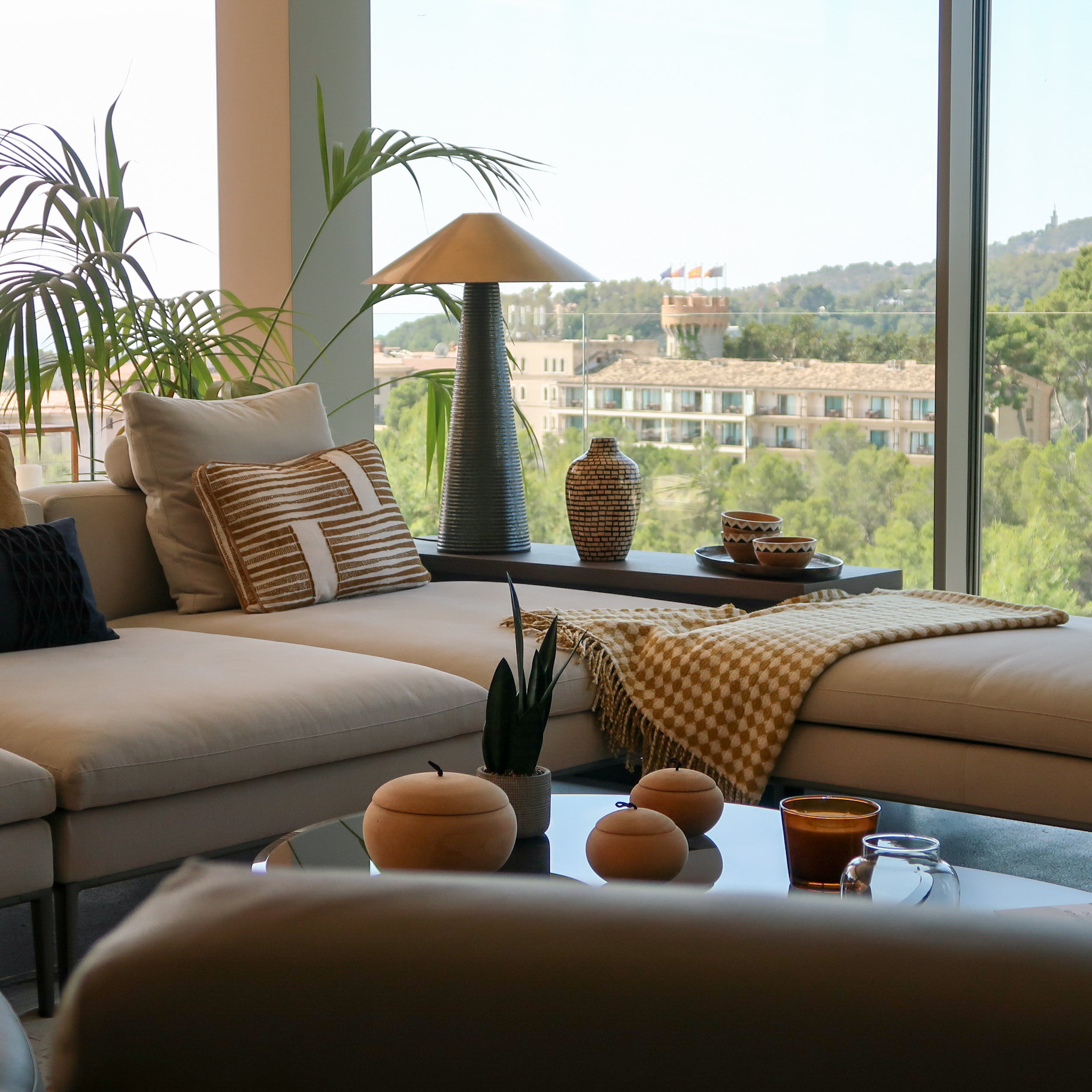 Living room with Cattelan Italia Coffee Table in bronze and smoked glass, B&B Italia sofa and leather armchairs, Burel Factory throw, Visual Comfort lamp and view of Marriott Castillo Hotel Son Vida in the background. Rialto Living accessories.