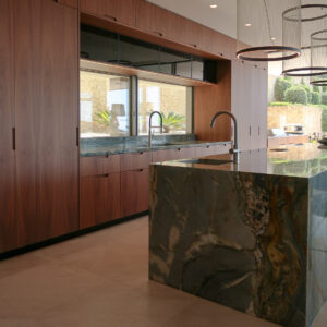 Bespoke walnut kitchen units and kitchen island clad in blue quartzite stone with gold veining. Vibia Array pendant lights.