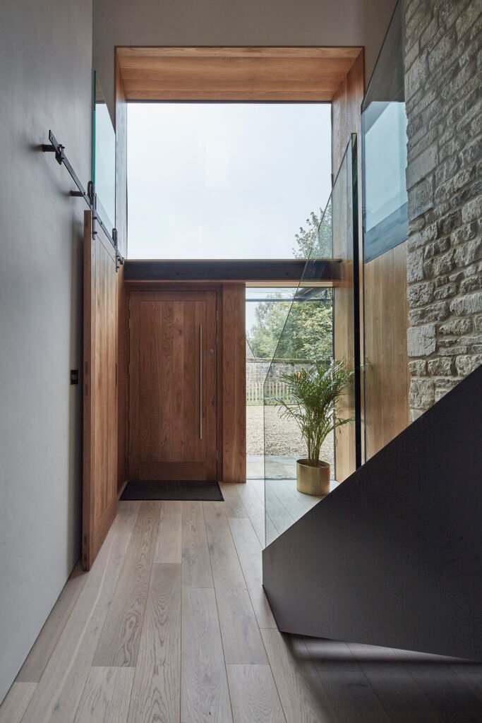 Modern entry way with large glass opening above the solid timber door.