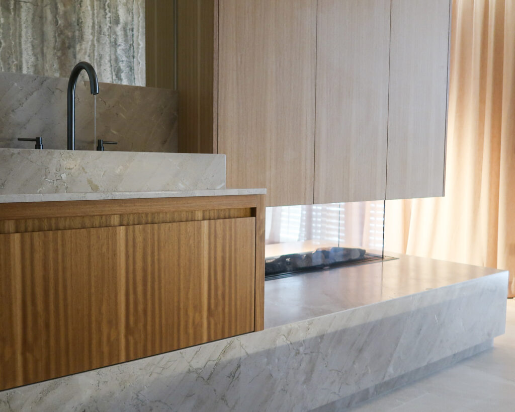 Bespoke bathroom and gas fireplace cabinetry with Grohe Atrio tap. Natural stone on floor, walls and sinks.